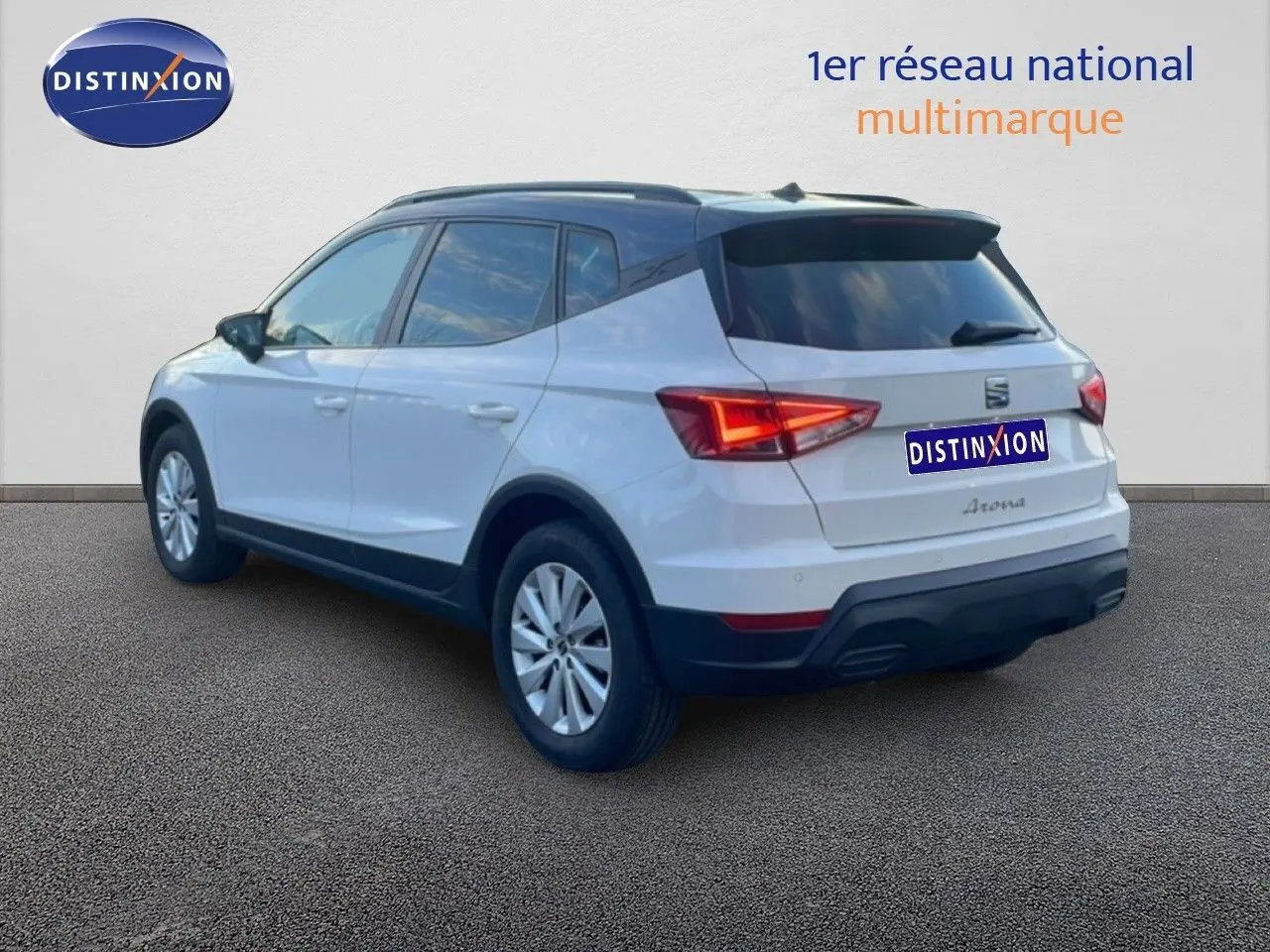 Vue 3/4 arrière droite d'un SEAT Arona blanc avec toit gris, feux arrière allumés et jantes alliage.