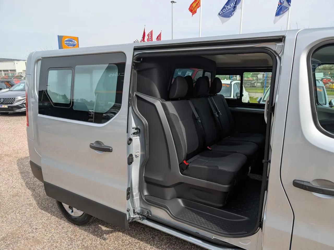 Vue latérale gauche d’un Renault Trafic Fourgon gris avec porte coulissante ouverte dévoilant la banquette arrière 3 places.
