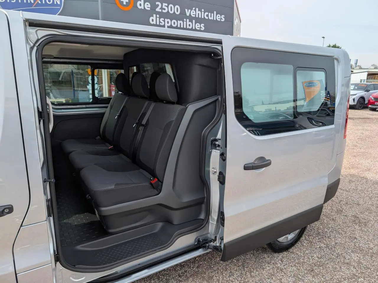 Vue côté droit sur l'ouverture de la porte coulissante d'un Renault Trafic gris avec banquette arrière 3 places.