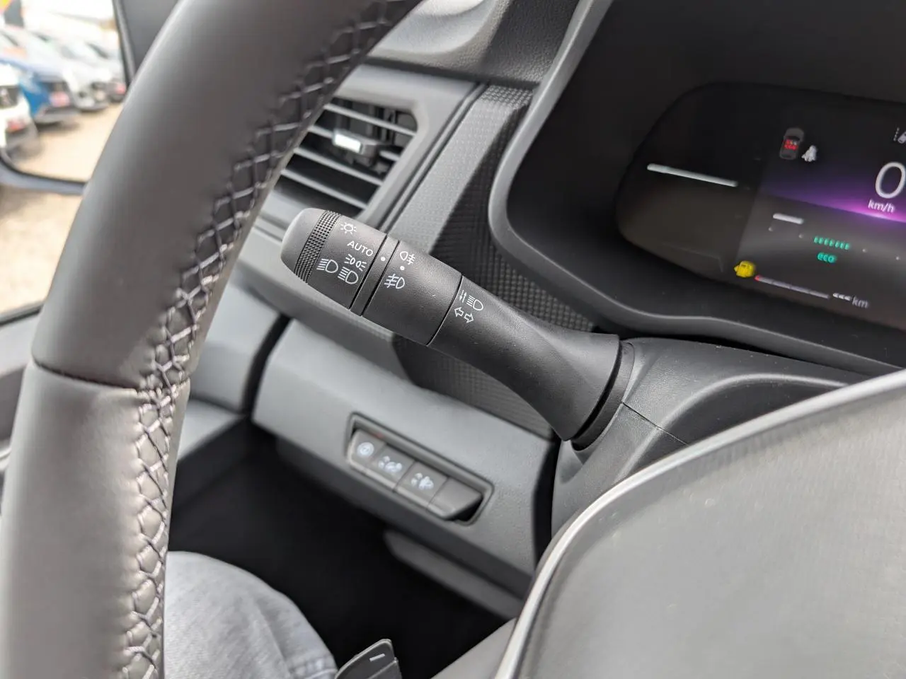 Gros plan sur la manette des feux à gauche du volant dans l’habitacle gris du Renault Trafic Fourgon 2025.