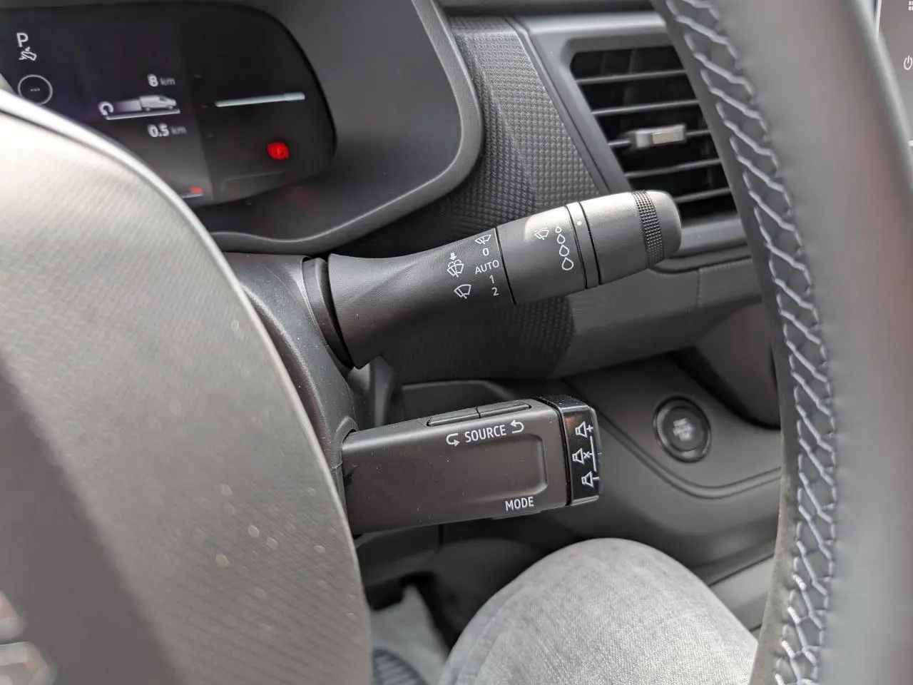 Gros plan sur la commande multifonction noire à gauche du volant dans l’habitacle gris du Renault Trafic Fourgon 2025.