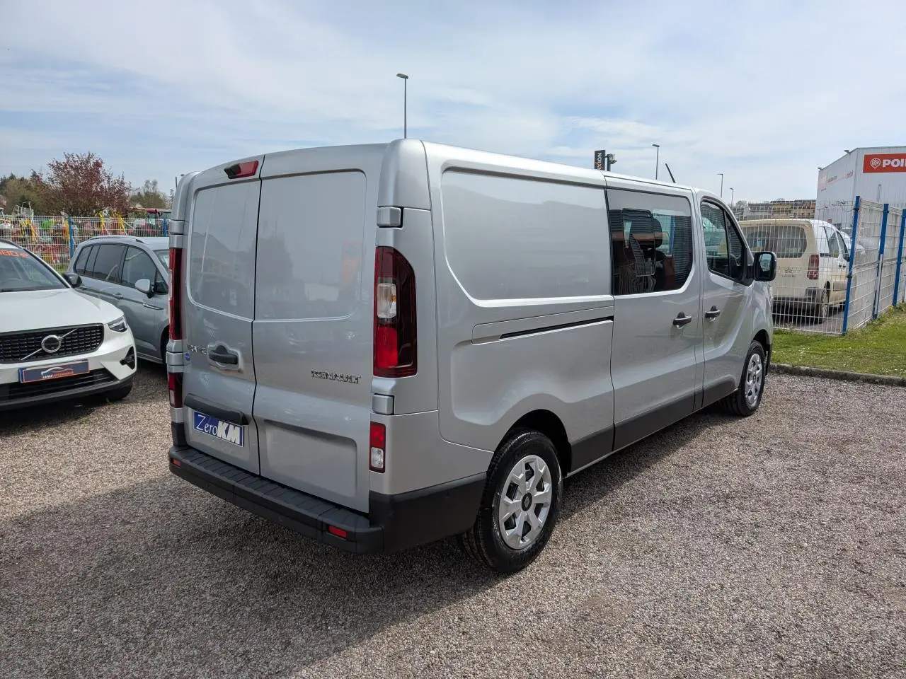 Renault Trafic Fourgon gris Highland vu en 3/4 arrière droit, avec portes arrière tôlées et enjoliveurs 16 pouces.