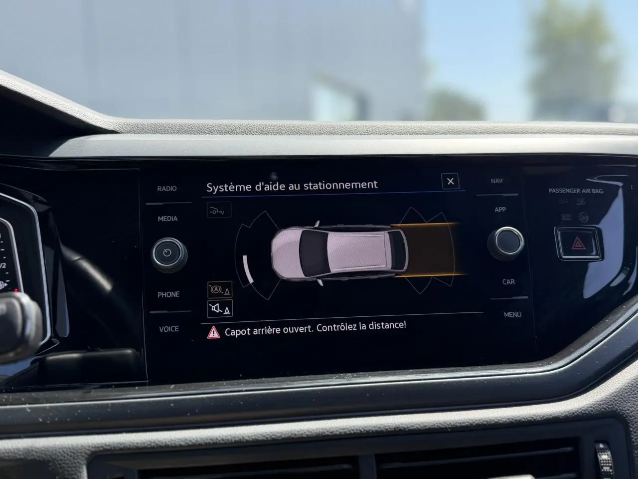 Écran central du Volkswagen Taigo TSI 116 DSG R-Line 2025 montrant l’aide au stationnement avec alerte capot arrière ouvert.