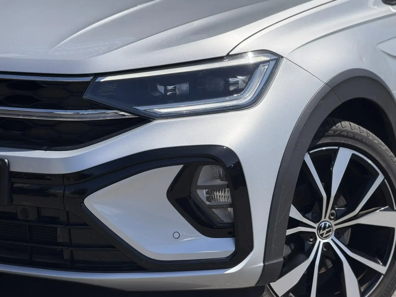 Gros plan sur l'avant droit argent Reflex du Volkswagen Taigo 2025 avec phares Matrix LED et jante alliage 18 pouces.