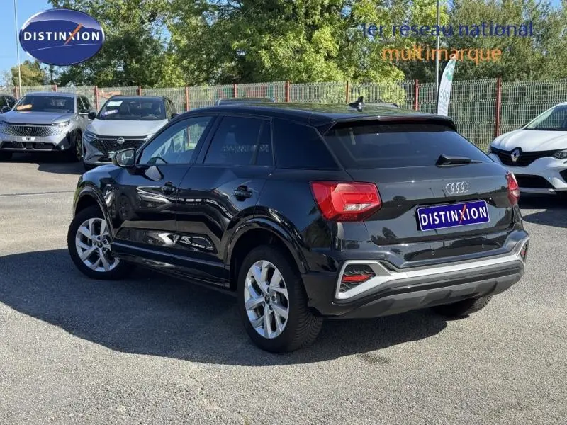 Audi Q2 35 TFSI S line noir Mythic métallisé, vue 3/4 arrière côté gauche, avec jantes argentées et feux rouges distinctifs.
