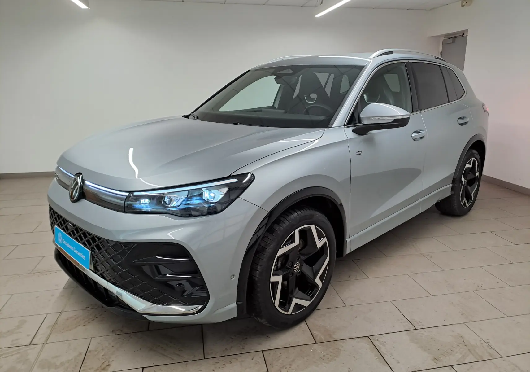 Volkswagen Tiguan 2.0 TDI 150 DSG7 R-Line argent Dolomite, vue 3/4 avant avec phares LED Matrix allumés.