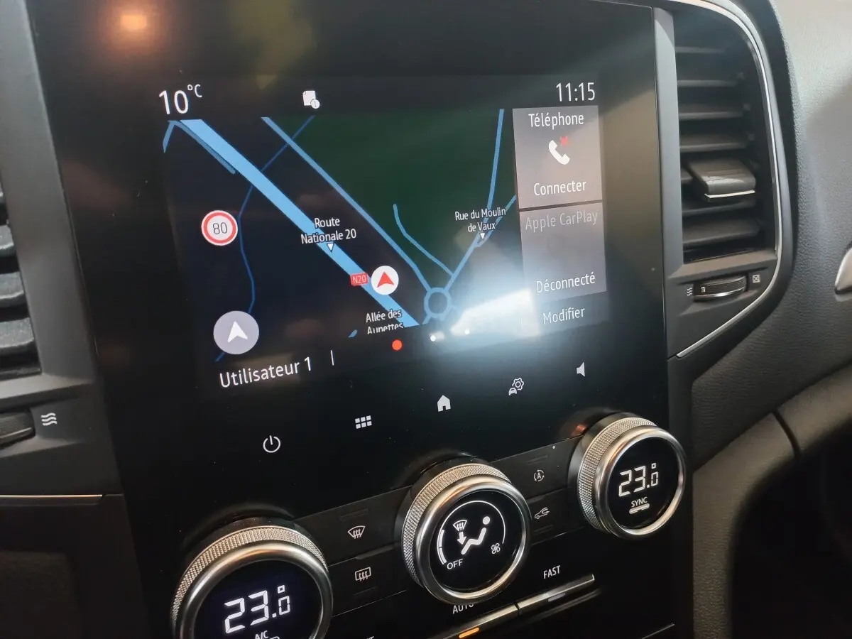 Vue rapprochée de l’écran tactile central et des commandes de climatisation d’une Renault Mégane Business gris foncé de 2022.