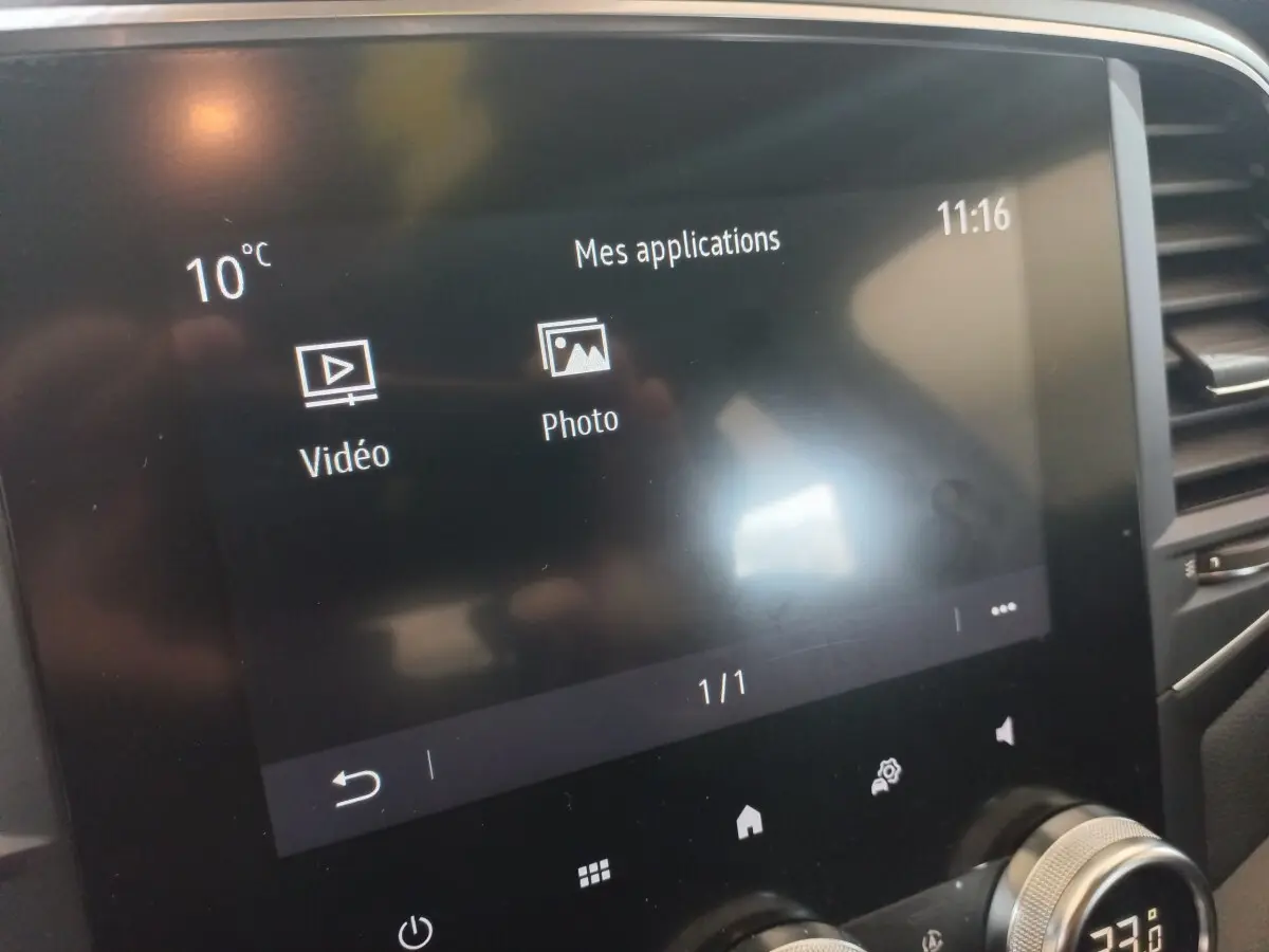 Écran tactile central affichant les applications vidéo et photo dans l’habitacle d’une Renault Mégane Business gris foncé.