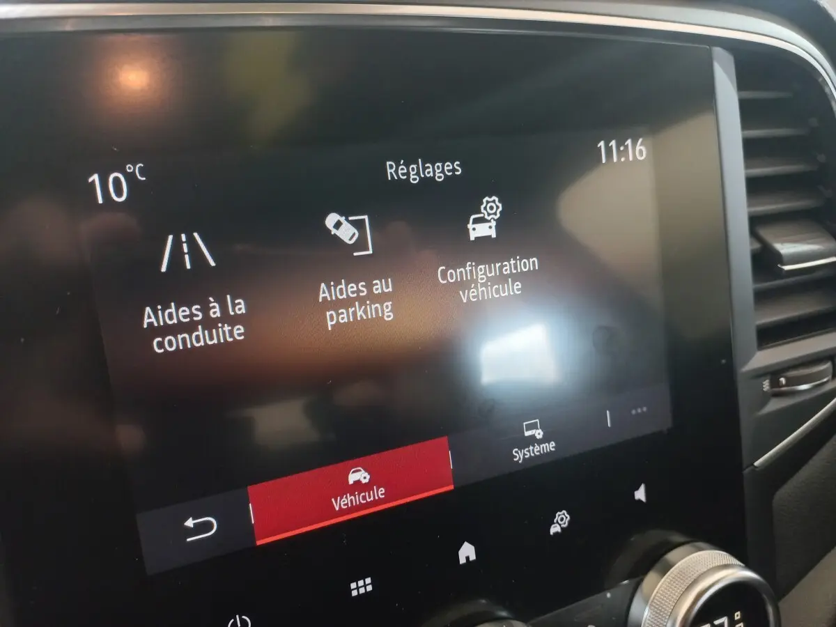 Écran tactile central de la Renault Mégane Business gris foncé affichant les réglages d’aides à la conduite et au parking.