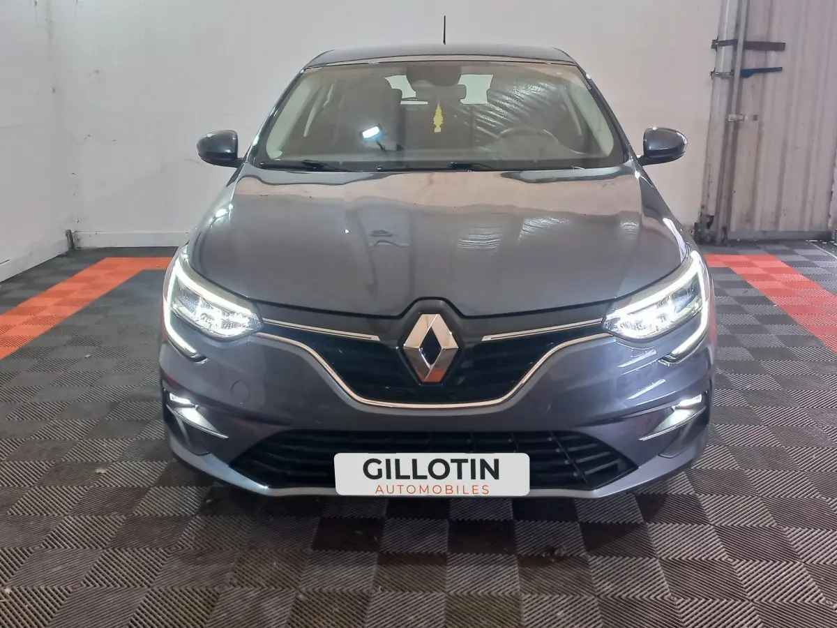 Vue frontale d'une Renault Mégane Business TCe 115 gris foncé avec phares LED allumés dans un garage.