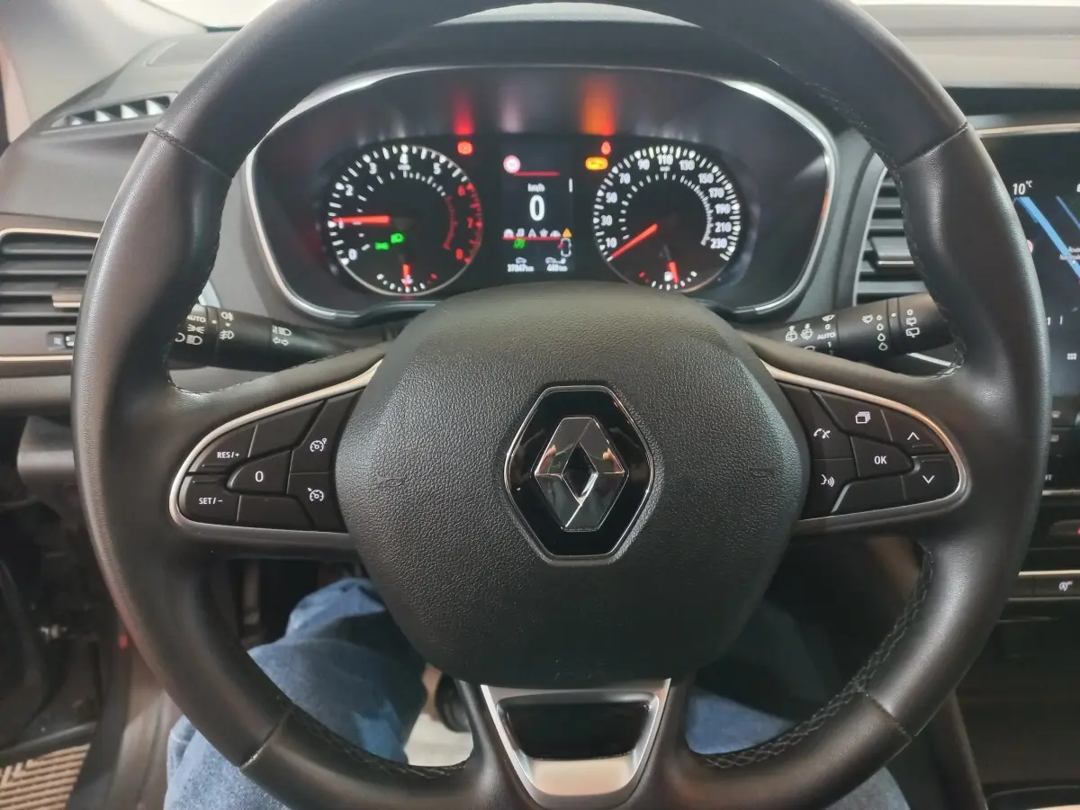 Vue rapprochée du volant multifonctions noir de la Renault Mégane Business 2022 avec tableau de bord digital allumé.