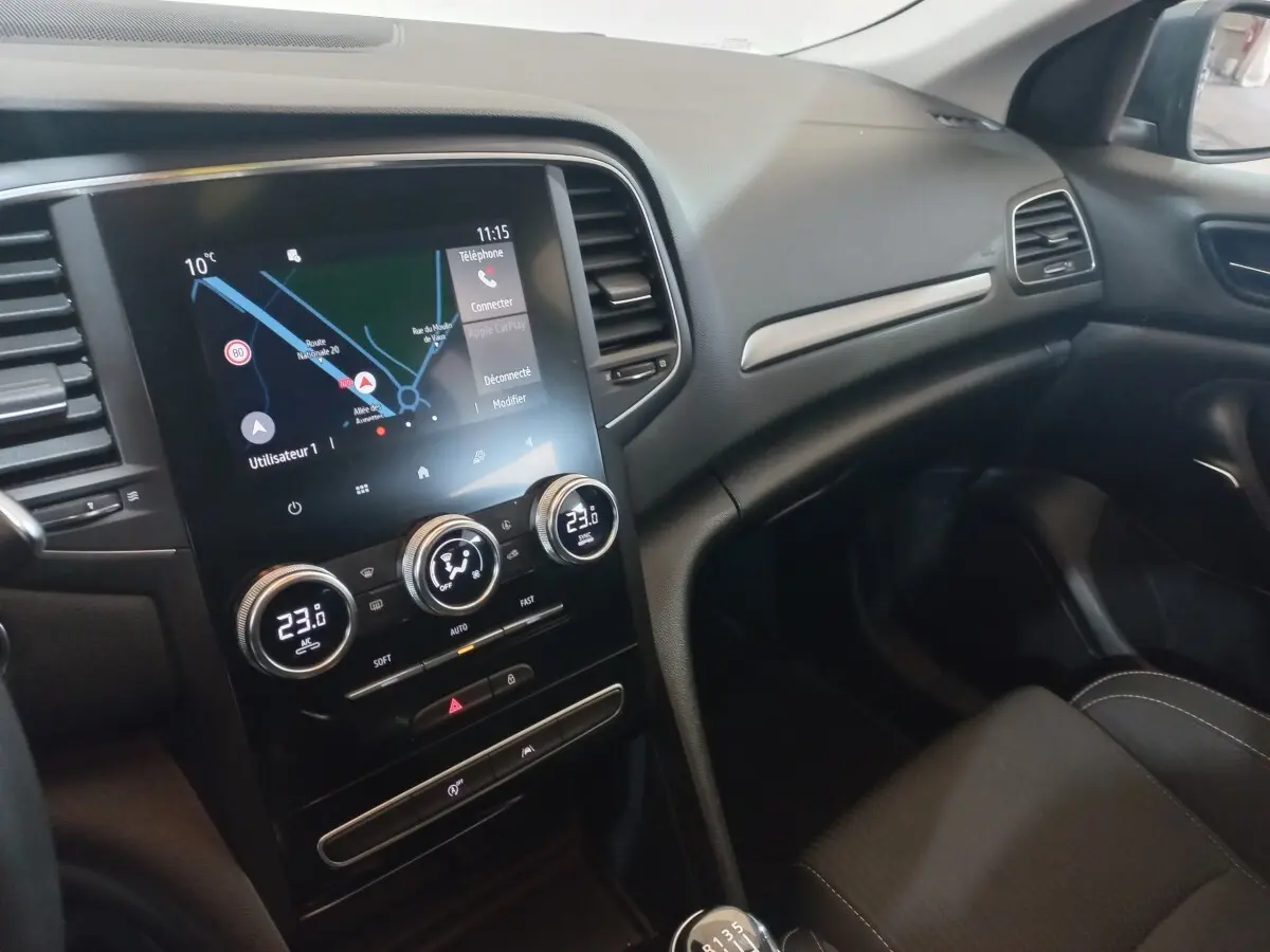 Vue intérieure côté passager de la Renault Mégane Business 2022, avec écran tactile et commandes de climatisation visibles.