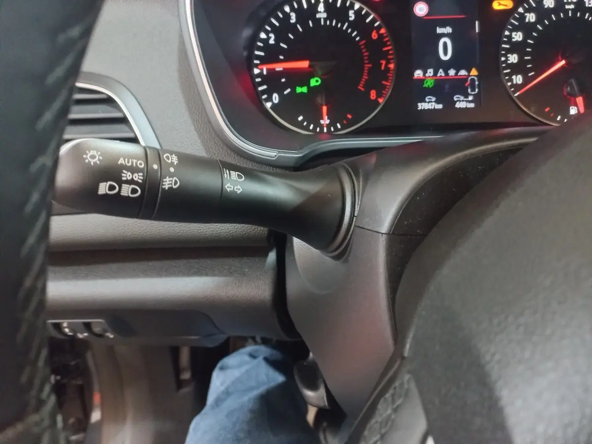 Gros plan sur le commodo gauche et le tableau de bord numérique de la Renault Mégane Business gris foncé, affichage multifonctions allumé.