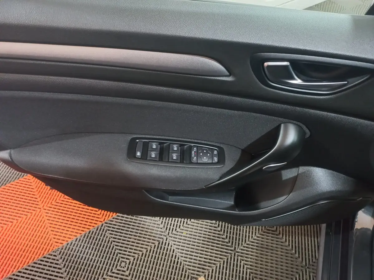 Vue rapprochée de la porte côté gauche de la Renault Mégane Business gris foncé, avec commandes électriques des vitres et poignée noire.