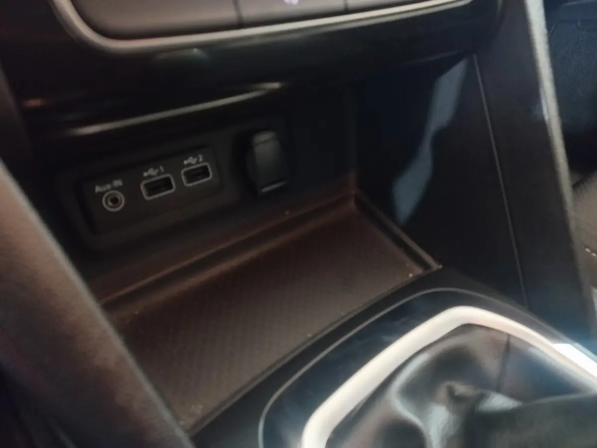 Gros plan sur la console centrale intérieure de la Renault Mégane Business gris foncé, avec ports USB et prise auxiliaire visibles.