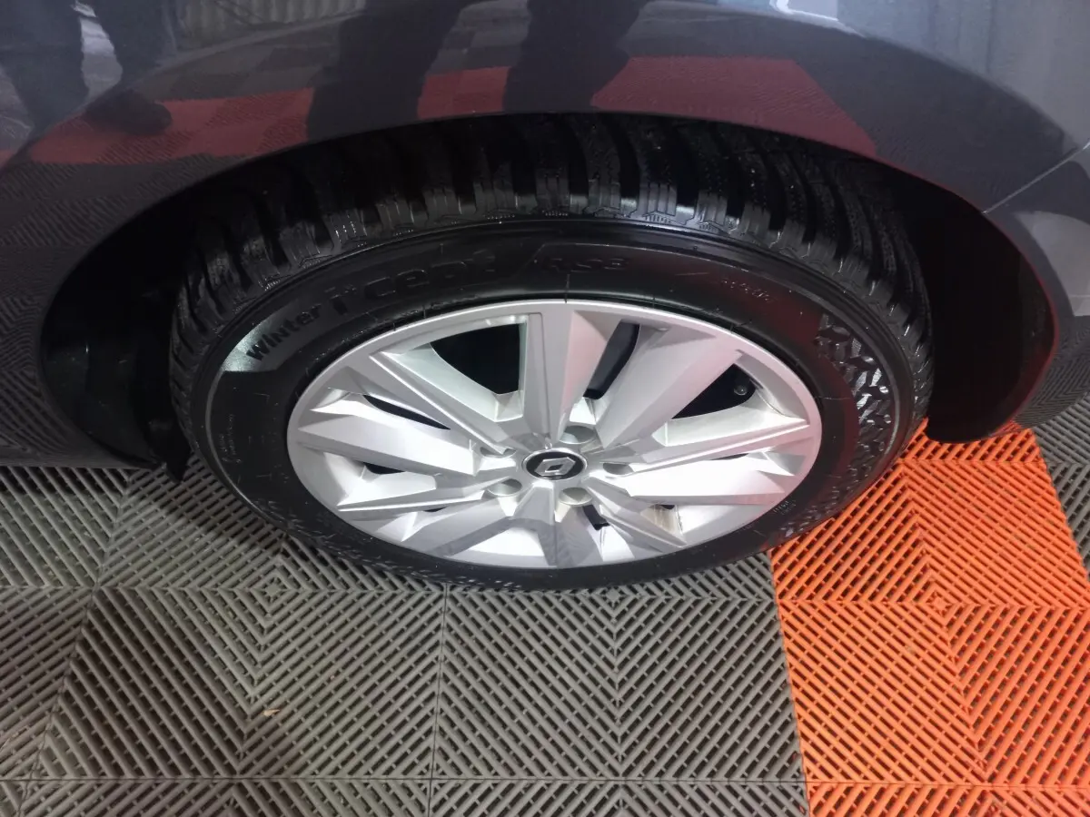 Gros plan sur la roue avant droite d’une Renault Mégane Business gris foncé, jante alliage argentée visible.