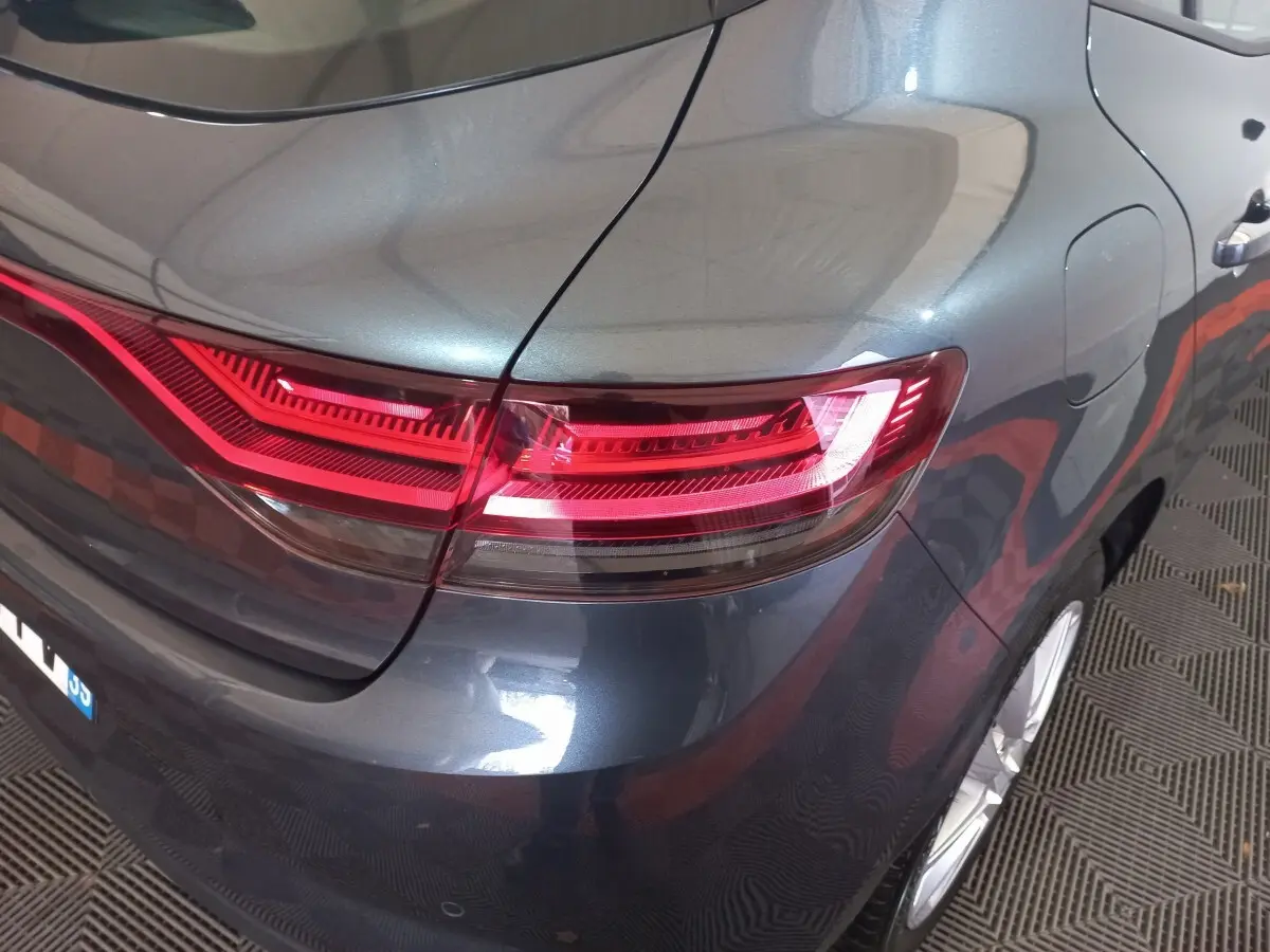 Vue 3/4 arrière droite d'une Renault Mégane Business gris foncé, mettant en valeur le feu arrière LED et la carrosserie brillante.
