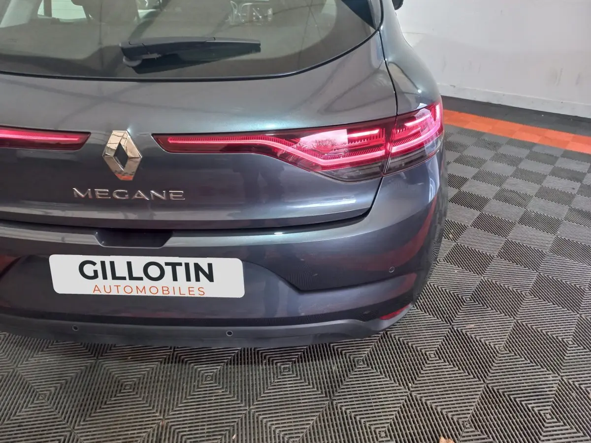 Vue arrière de la Renault Mégane gris foncé, mettant en valeur les feux LED et le logo central sur un sol damier.