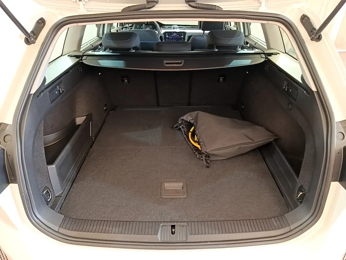 Coffre ouvert d’une Volkswagen Passat blanche hybride rechargeable, vue arrière montrant un espace de chargement spacieux avec un sac noir.