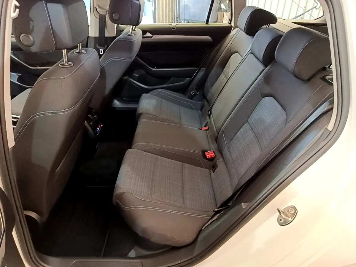 Vue intérieure côté droit des sièges arrière gris foncé avec surpiqûres blanches de la Volkswagen Passat hybride rechargeable blanche.