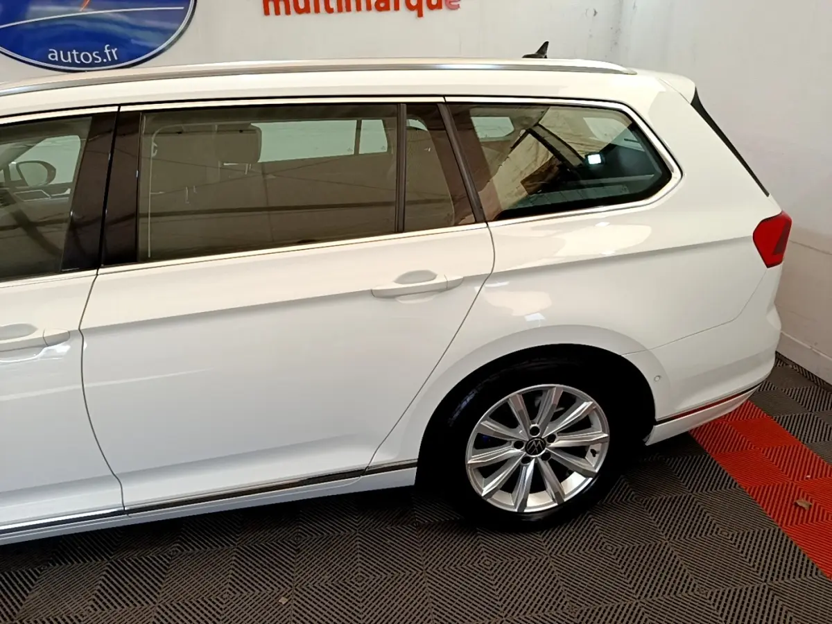 Vue côté droit arrière d'une Volkswagen Passat blanche break avec jante alliage et vitres teintées.