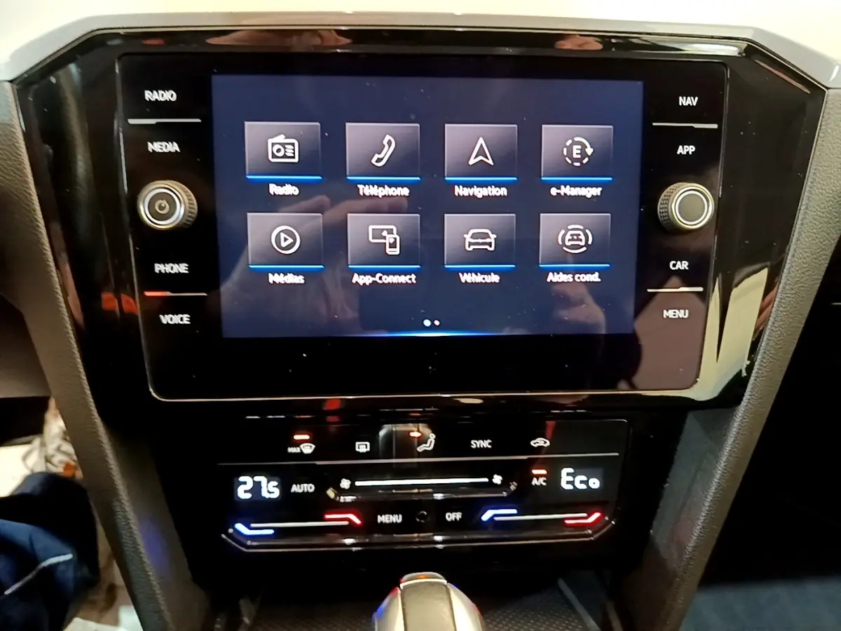 Vue rapprochée de l'écran tactile central et de la console de climatisation d'une Volkswagen Passat blanche hybride rechargeable.