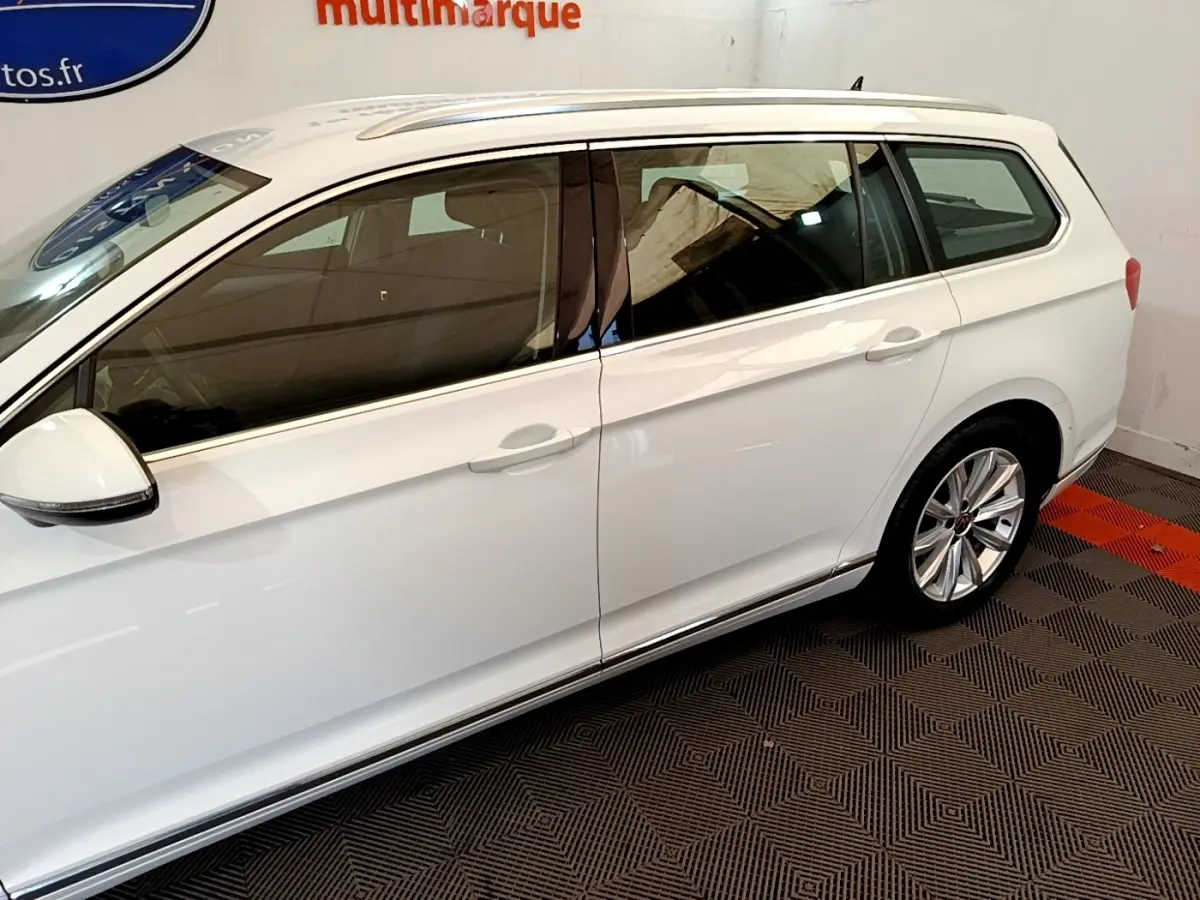 Vue de profil côté gauche d'une Volkswagen Passat break hybride blanche avec jantes alliage et vitres teintées.