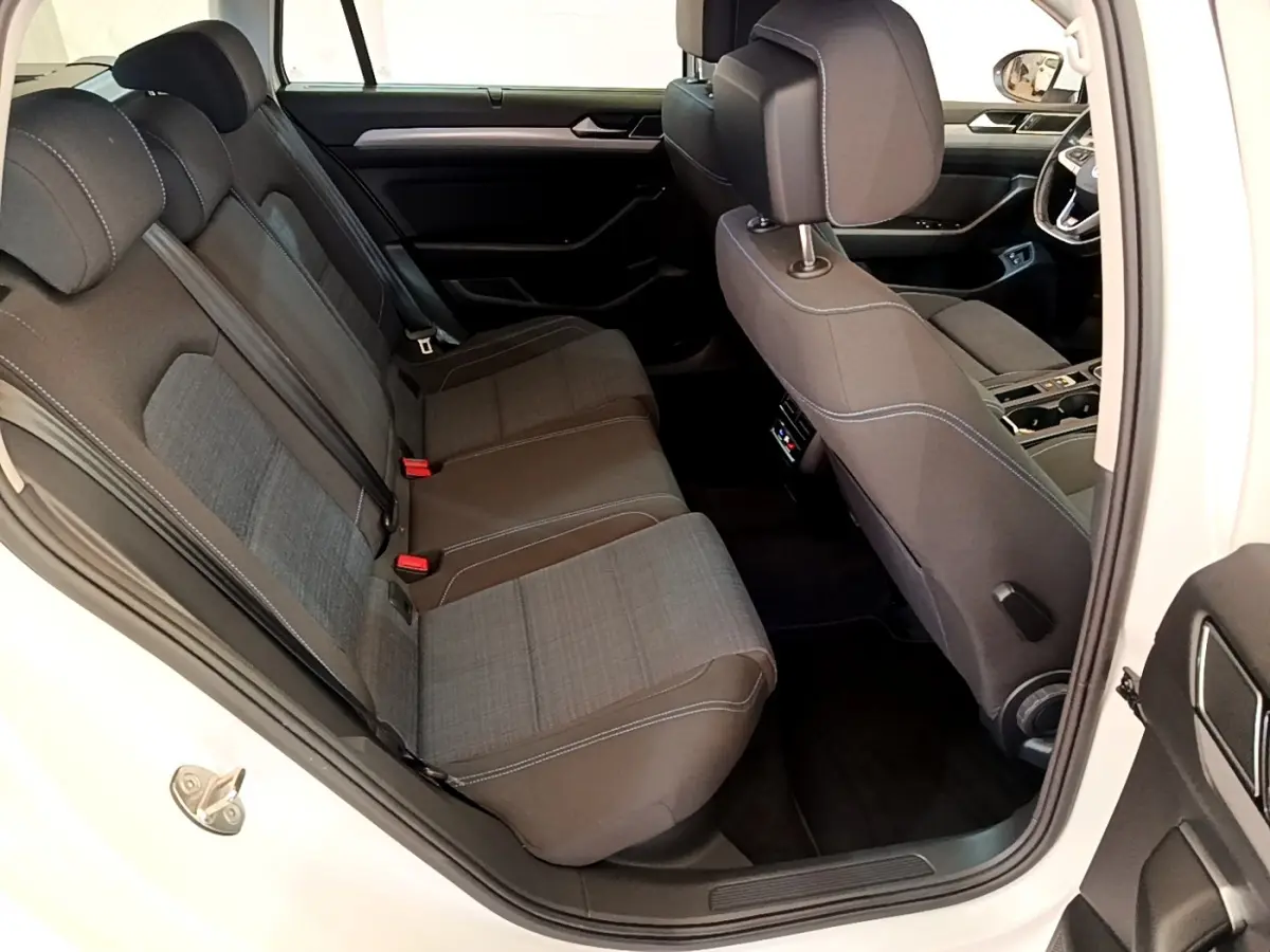 Vue intérieure côté droit montrant les sièges arrière gris foncé et la porte ouverte d'une Volkswagen Passat blanche hybride rechargeable.