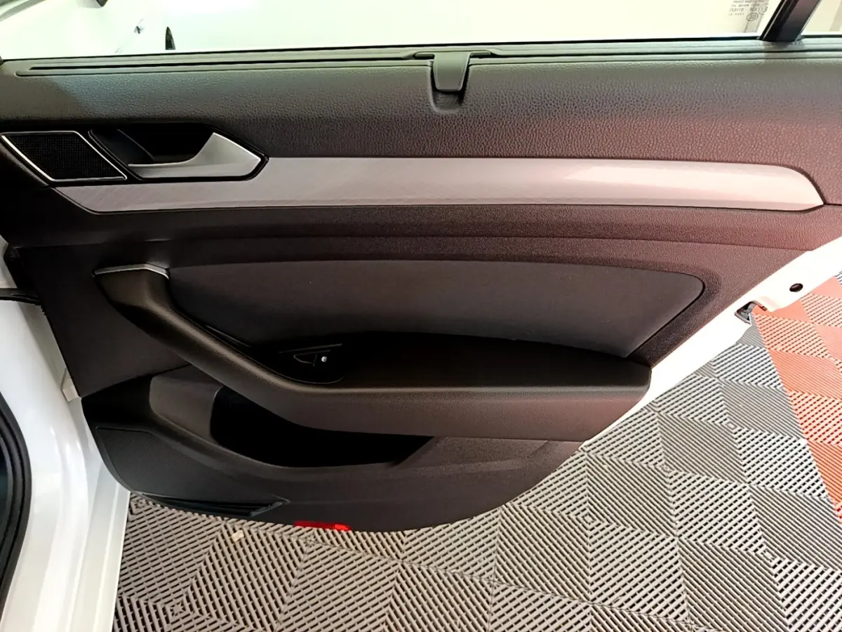 Vue rapprochée de la porte avant gauche blanche de la Volkswagen Passat 2021 avec garniture noire et insert décoratif gris.