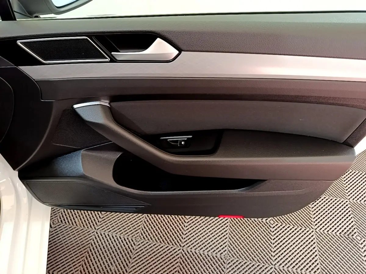 Vue rapprochée de la porte avant gauche blanche d'une Volkswagen Passat GTE 2021 avec poignée et commande de verrouillage.