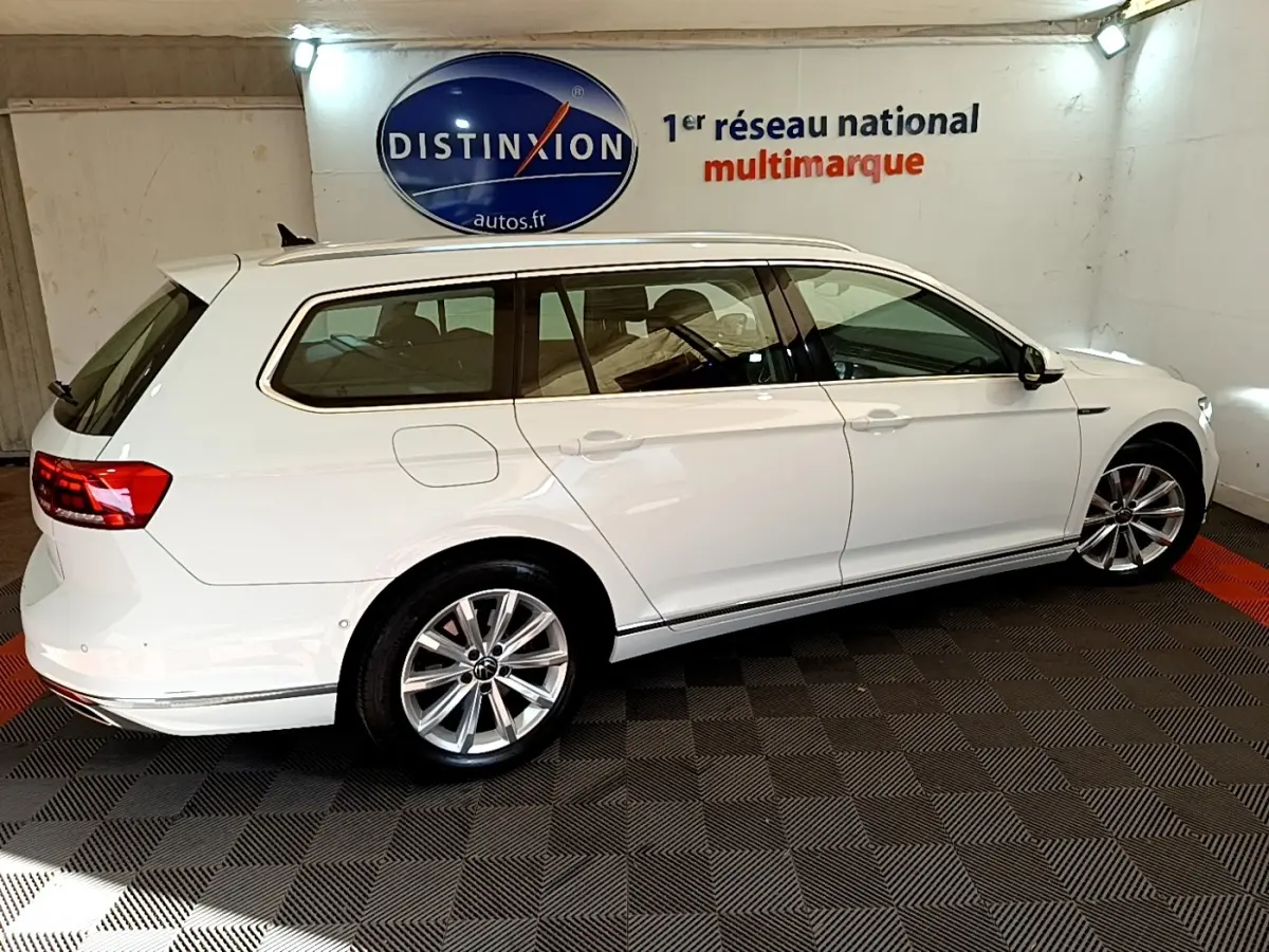 Volkswagen Passat break blanc vue de profil côté gauche dans un showroom avec logo Distinxion en arrière-plan.