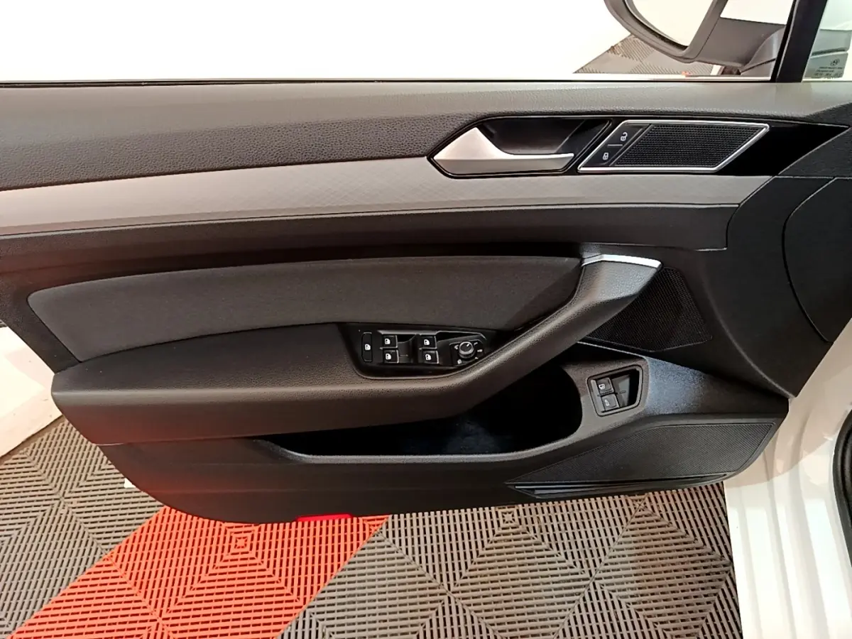 Vue latérale du panneau de porte avant gauche noir avec commandes électriques sur Volkswagen Passat blanche hybride rechargeable 2021.