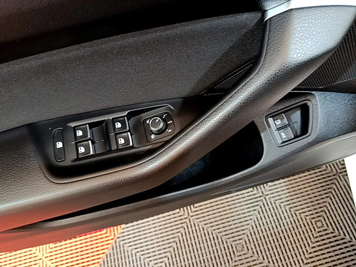 Gros plan sur la commande des vitres et rétroviseurs côté conducteur de la Volkswagen Passat blanche hybride rechargeable.