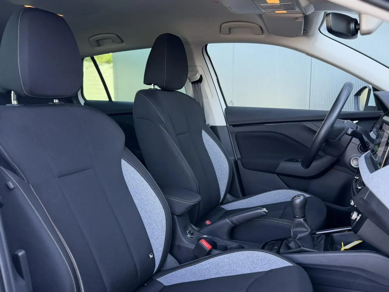 Vue intérieure côté droit de la Skoda Scala TSI 116, sièges tissu noir et gris avec surpiqûres blanches.