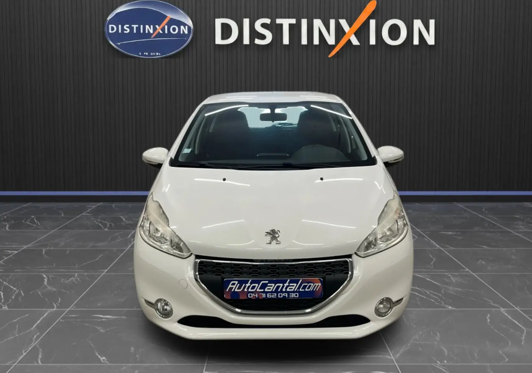 Peugeot 208 blanc vue de face, mettant en valeur sa calandre noire et ses phares effilés dans un showroom.