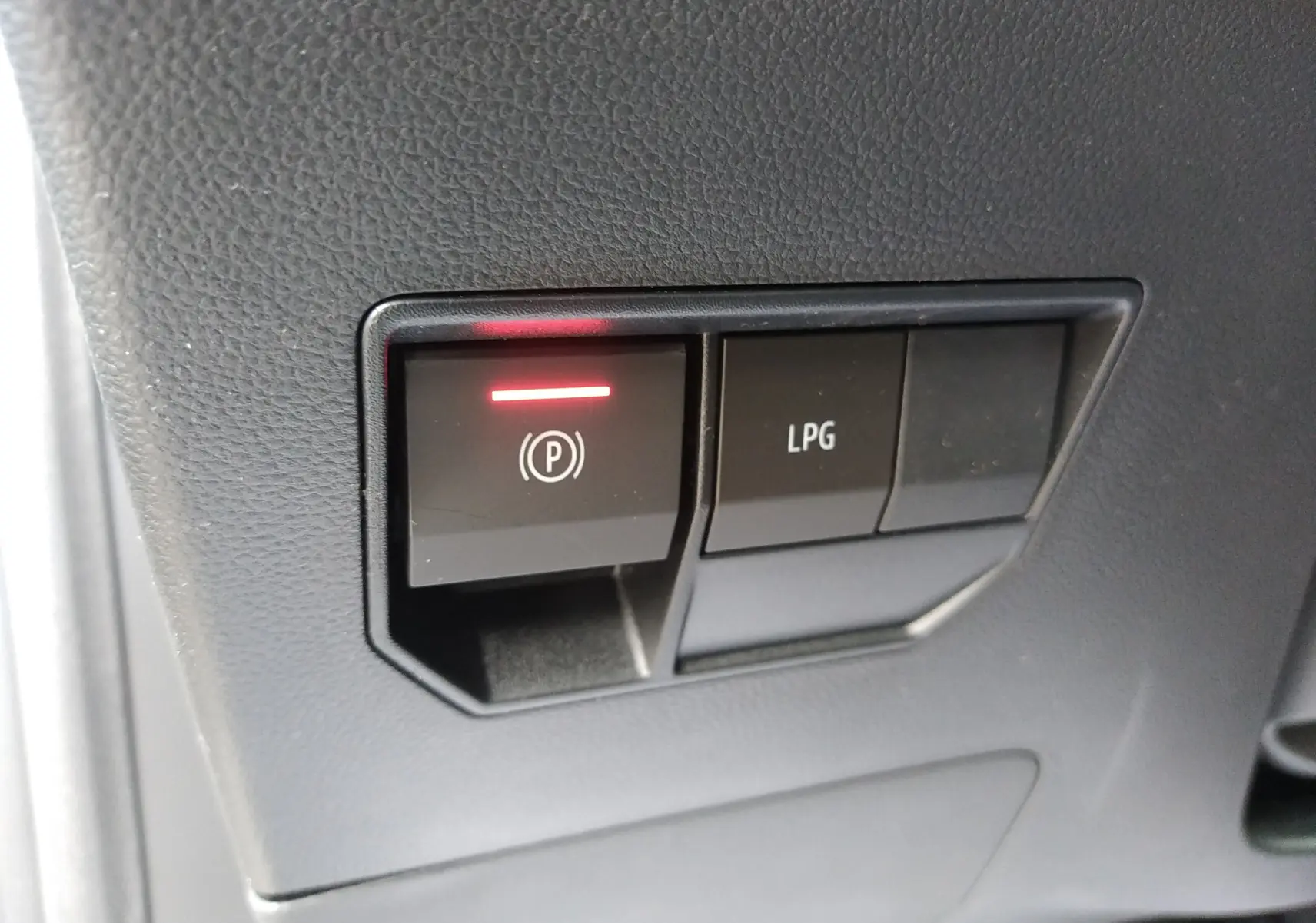 Gros plan sur les boutons du frein à main électronique et mode GPL dans l'habitacle du Dacia Duster Hybrid-G 150 ch.