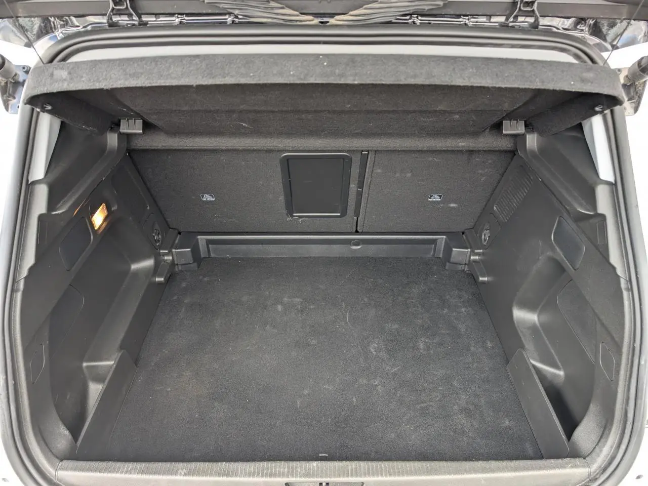 Coffre ouvert vu de l'arrière d'un Opel Grandland blanc métallisé, espace de chargement vide et tapis noir.