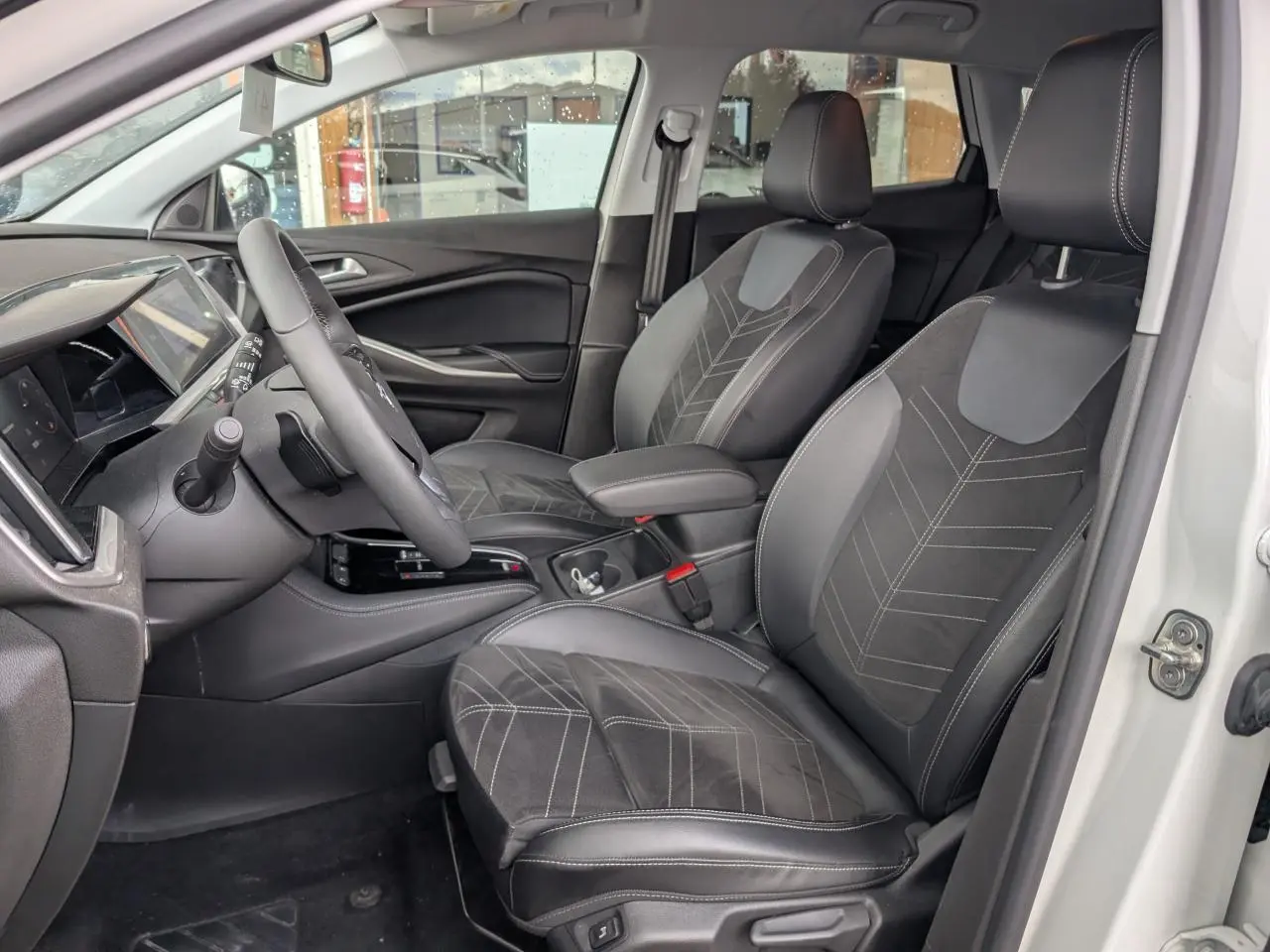 Vue intérieure côté conducteur de l’Opel Grandland blanc, sièges en Alcantara noir avec surpiqûres contrastées.