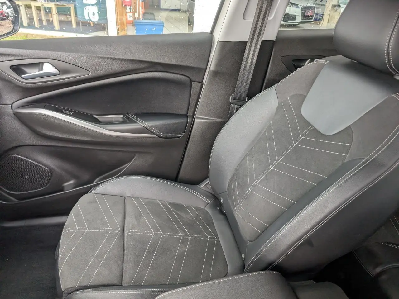 Vue intérieure côté passager avant de la sellerie Alcantara/TEP noire avec surpiqûres blanches de l'Opel Grandland 2024.