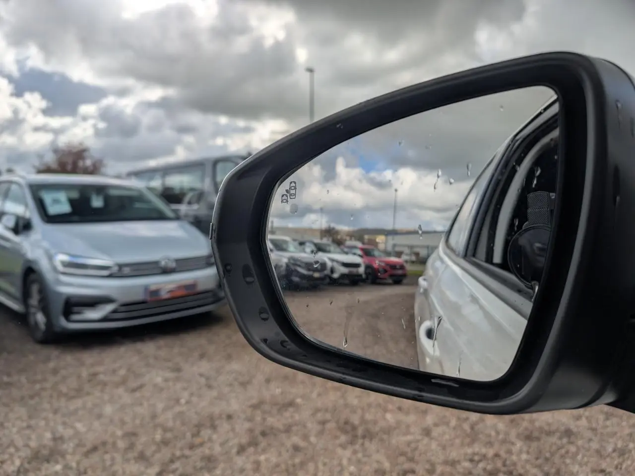 Rétroviseur côté droit d’un Opel Grandland blanc métallisé, vue partielle du véhicule et parking en arrière-plan.