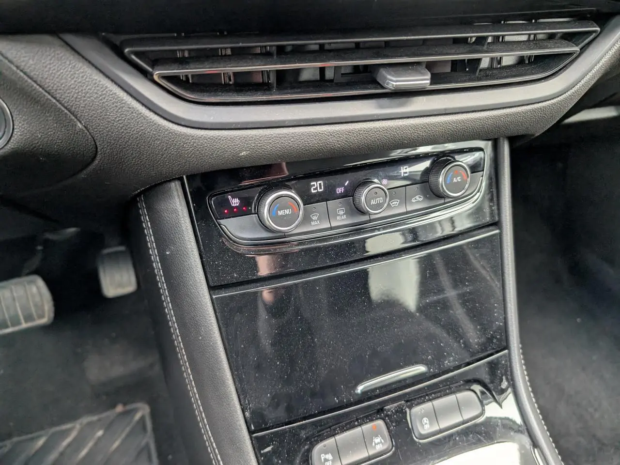Vue rapprochée de la console centrale noire brillante avec commandes de climatisation et boutons multifonctions de l'Opel Grandland 2024.