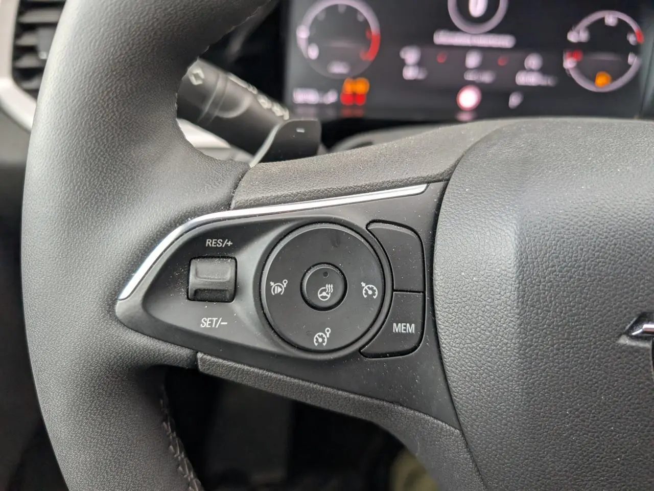 Gros plan sur les commandes de régulateur de vitesse et chauffage du volant sur le côté gauche du volant noir d’un Opel Grandland.