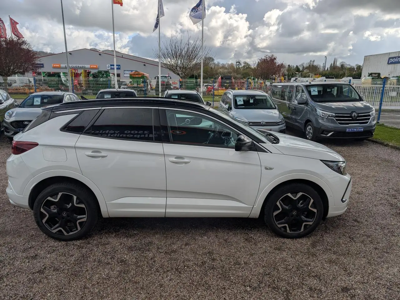 Opel Grandland blanc métallisé vu de profil côté gauche avec toit noir et jantes alliage noires.