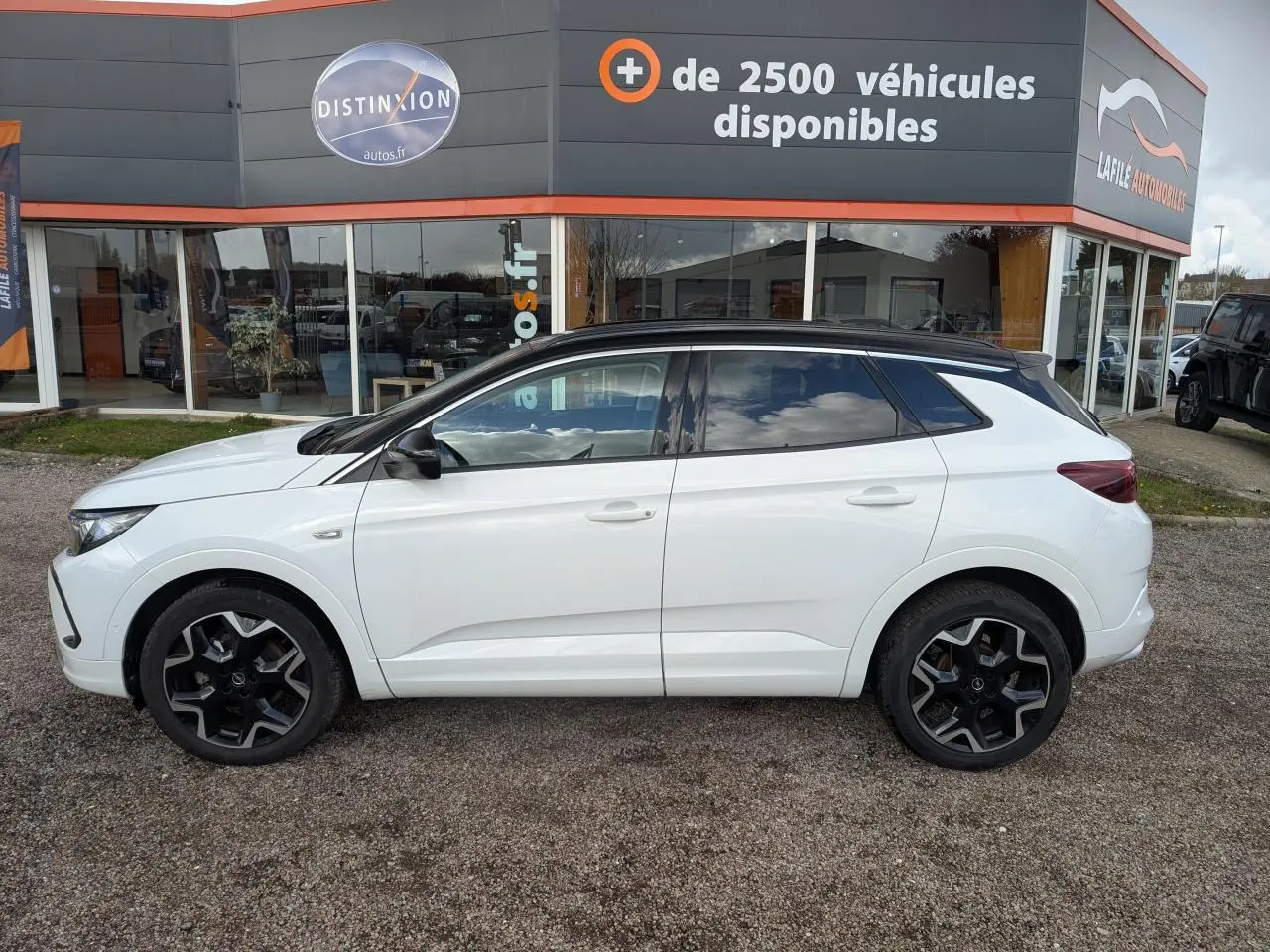 Opel Grandland 2024 blanc métallisé en profil droit, toit noir brillant et jantes alliage noires distinctives.