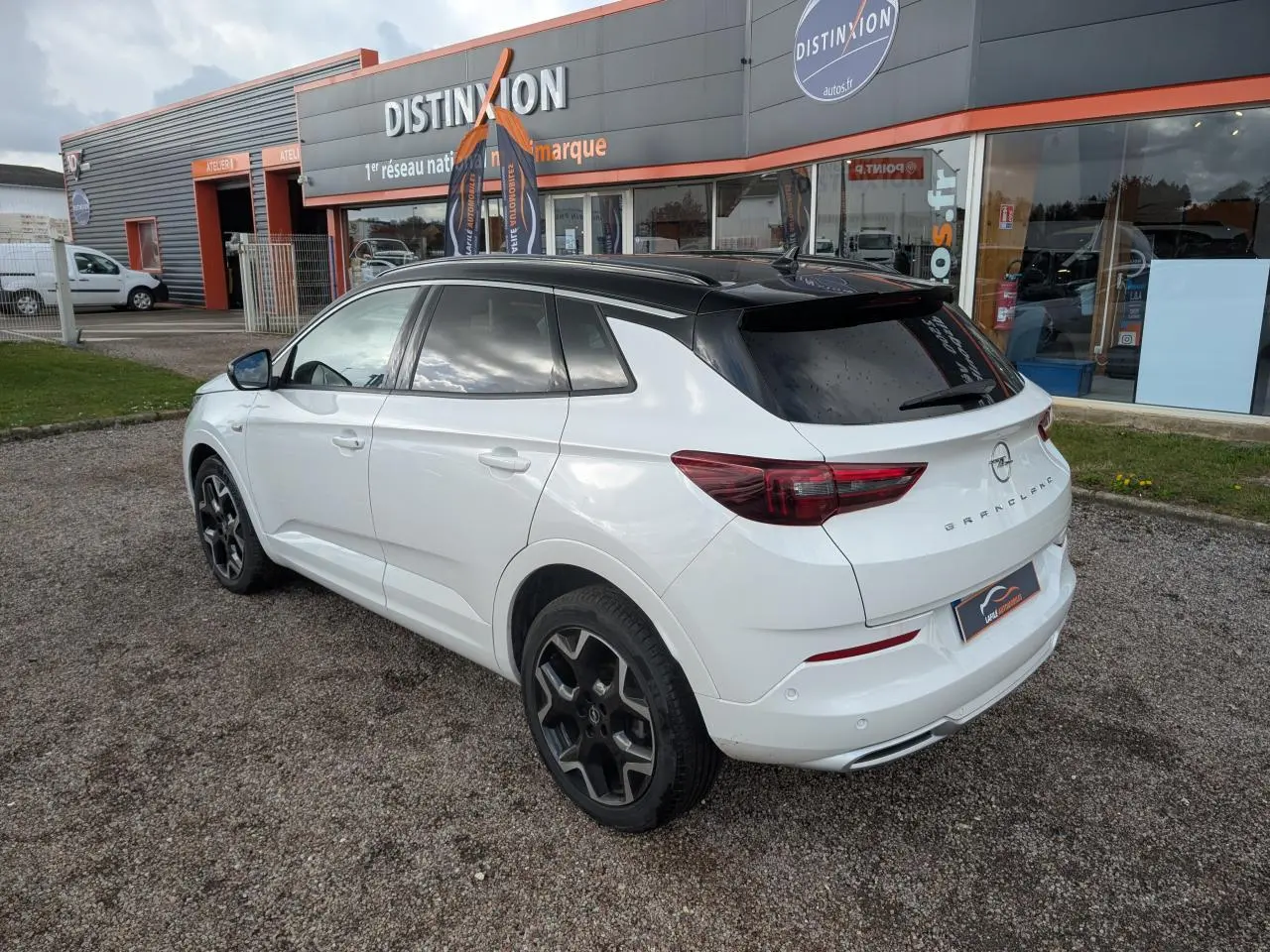 Opel Grandland blanc métallisé vue 3/4 arrière droit avec toit noir et jantes alliage noires.