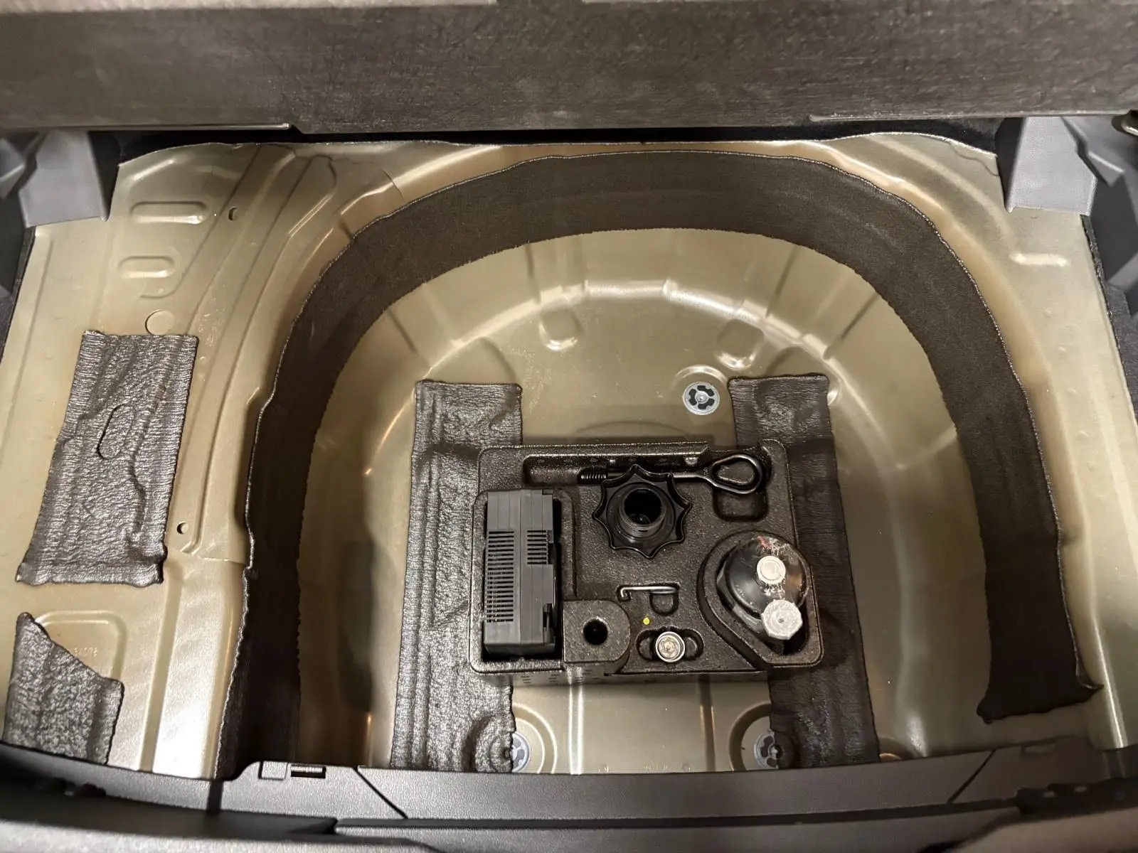 Coffre ouvert du Volkswagen T-cross noir intense 2024, montrant le rangement sous plancher avec outils intégrés.