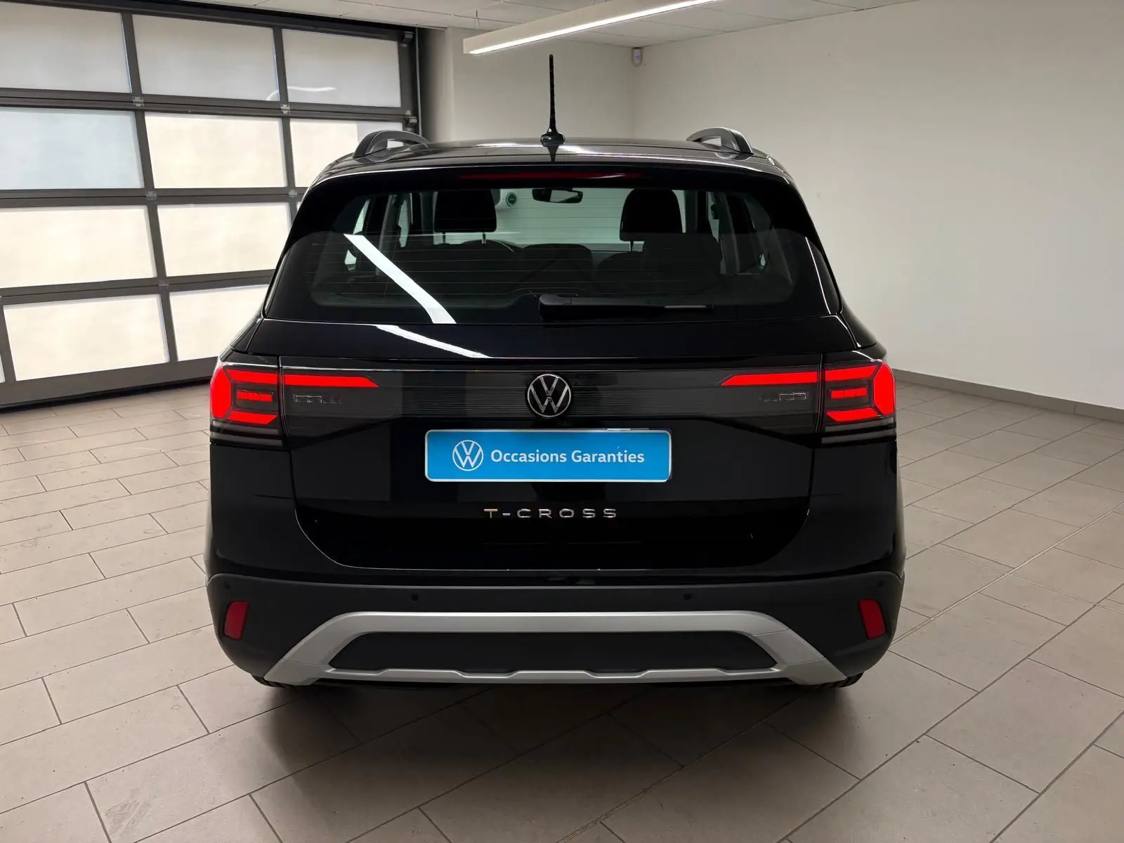 Vue arrière du Volkswagen T-Cross noir intense 2024 avec feux rouges allumés et logo VW bien visible.