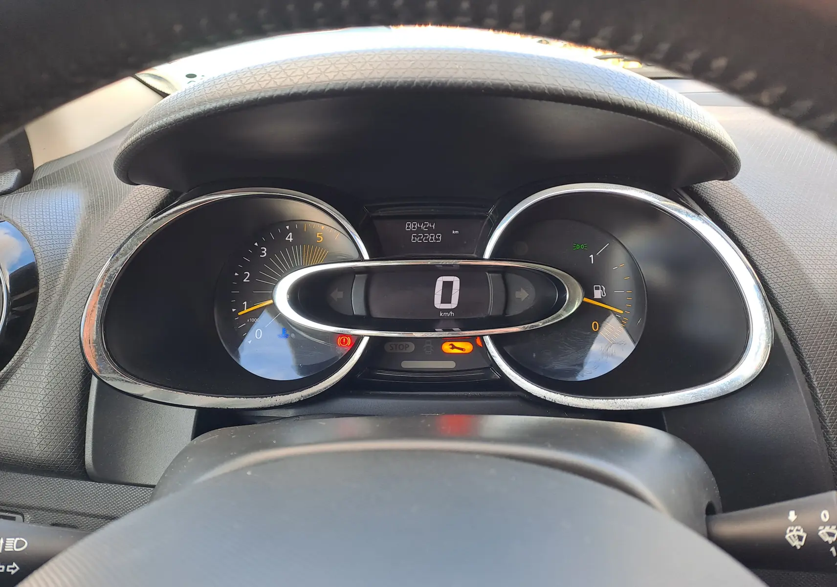 Vue rapprochée du tableau de bord de la Renault Clio IV, affichage digital au centre avec compte-tours et jauge à carburant.