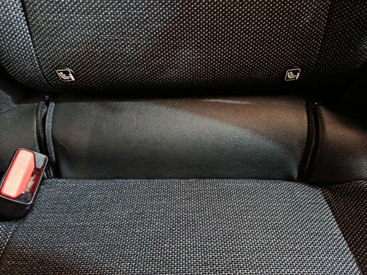 Gros plan sur la banquette arrière noire du Renault Captur 2024, montrant les fixations Isofix et une boucle de ceinture rouge.