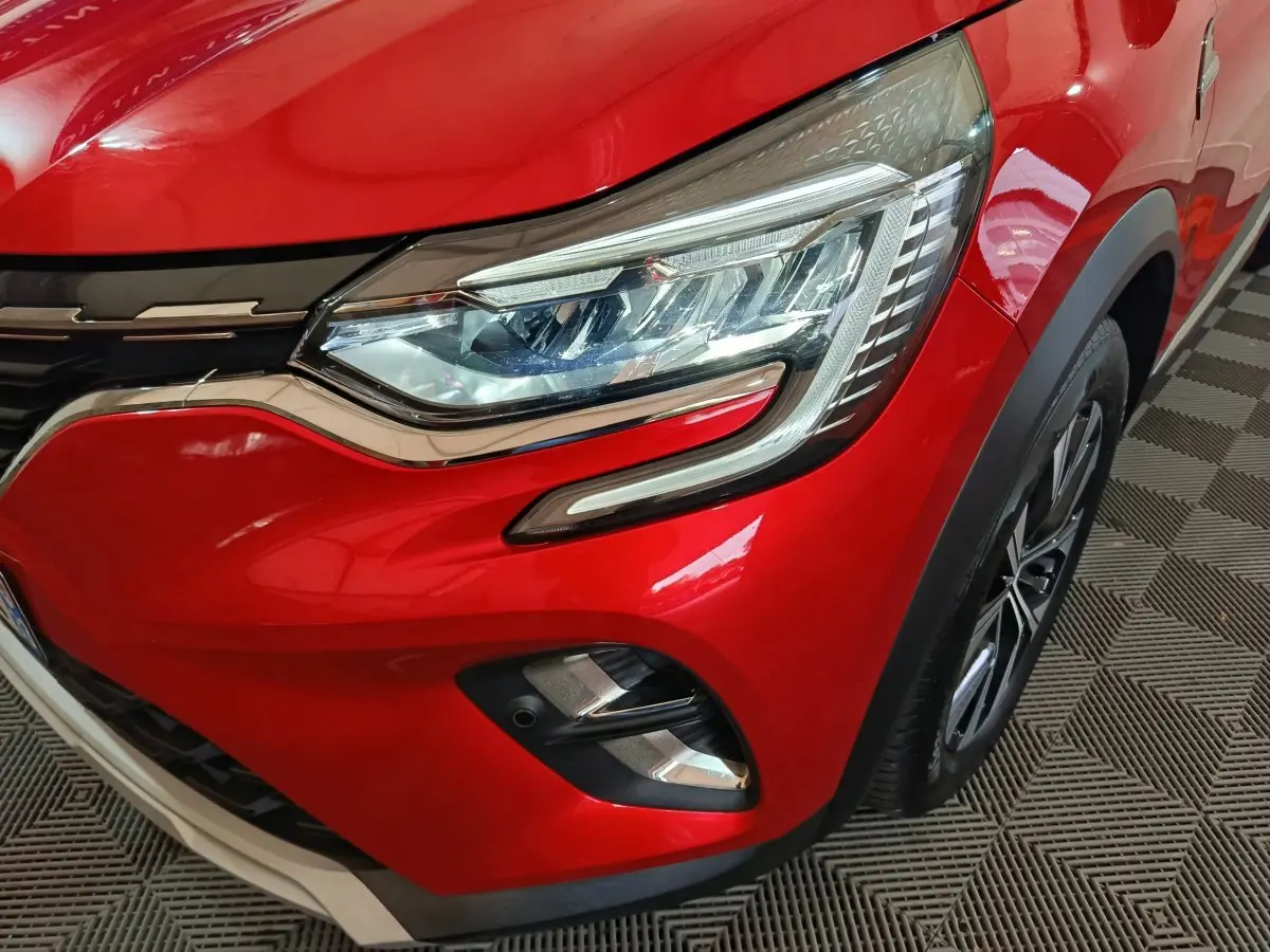 Gros plan sur l'avant droit rouge vif du Renault Captur 2024 avec phares LED et jante alliage visible.